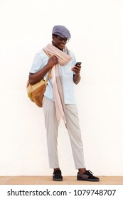 Full Length Portrait Of Trendy Young Black Guy Looking At Cell Phone And Smiling