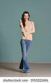 Full length portrait of trendy young woman in beige jersey longsleeve and straight blue jeans