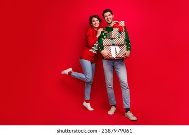 Full length portrait of two cheerful funky partners embrace hold pile stack festive giftbox isolated on red color background - Powered by Shutterstock