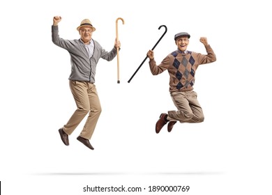 Full length portrait of two happy elderly men holding walking canes and jumping isolated on white background