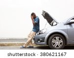 Full length portrait of upset young african man standing in front of a broken down car parked on the side of a road