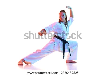Full length portrait of woman, female fighter in uniform with black belt isolated over white studio background. Concept of professional sport, recreation, art, hobby, culture. Copy space.