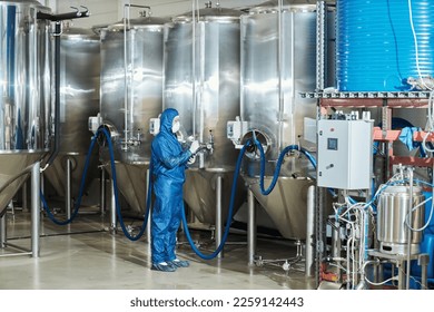 Full length portrait of worker in protective gear operating storage tanks equipment at factory, copy space - Powered by Shutterstock