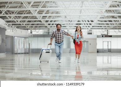 Full Length Portrait Of Worried Male And Woman Running With Baggage Indoor. They Late For Flight