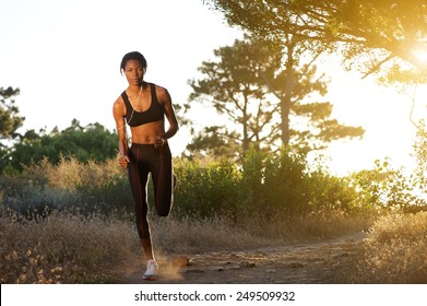 Full Length Portrait Of A Young African American Woman Jogging In Nature