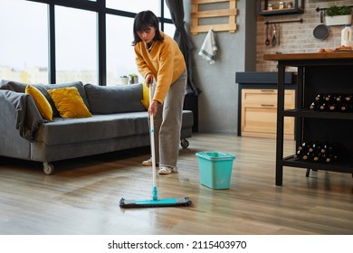 Full Length Portrait Of Young Asian Woman Mopping Floors While Cleaning Cozy Apartment