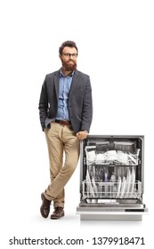 Full length portrait of a young bearded man posing next to a loaded dishwasher isolated on white background