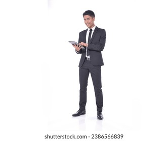 Full length portrait of young businessman using tablet standing isolated over white background - Powered by Shutterstock