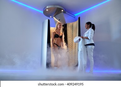 Full length portrait of young caucasian woman standing in a cryosauna, whole body cryotherapy.