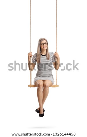 Full length portrait of a young cheerful woman sitting on a swing and smiling at the camera isolated on white background