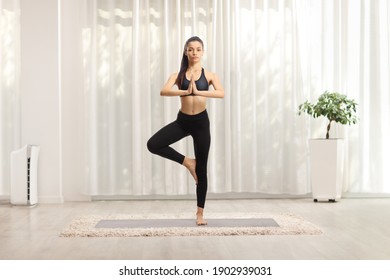 Full length portrait of a young female exercising a yoga pose on a mat at home