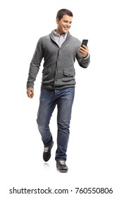 Full Length Portrait Of A Young Guy Using A Phone And Walking Towards The Camera Isolated On White Background