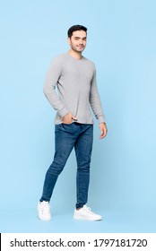 Full Length Portrait Of Young Handsome Caucasian Man Standing With Hand In Pocket While Looking At Camera In Isolated Studio Blue Background