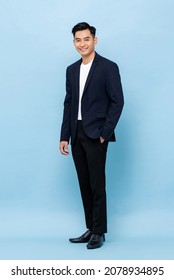 Full length portrait of young handsome southeast Asian millenial businessman looking at camera on light blue studio background - Shutterstock ID 2078934895