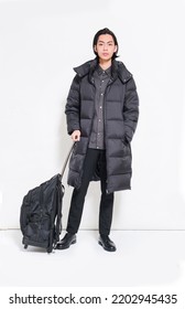 Full Length Portrait Of Young Handsome Man In Warm Winter Jacket Holding Hand Luggage Over Gray Background
	
