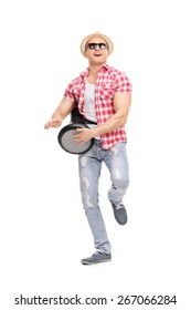 Full length portrait of a young joyful man playing on a doumbek and dancing isolated on white background