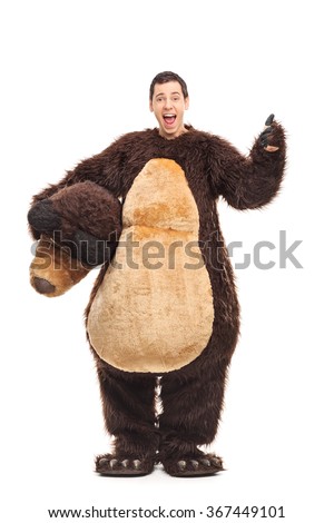 Full length portrait of a young joyful guy in a bear costume giving a thumb up isolated on white background
