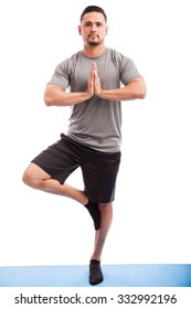 Full length portrait of a young Latin man doing a tree pose during yoga practice on a white background