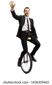 Full Length Portrait Of A Young Man In A Suit Riding A Unicycle And Waving At The Camera Isolated On White Background