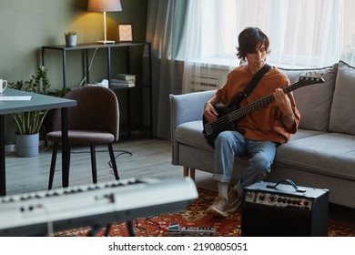 Full length portrait of young man playing electric guitar in cozy home music studio, copy space - Powered by Shutterstock