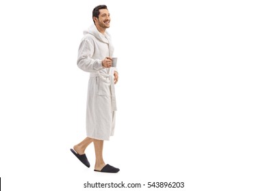 Full length portrait of a young man in a bathrobe holding a cup and walking isolated on white background - Powered by Shutterstock