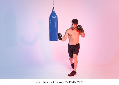 Full Length Portrait Of Young Sporty Guy Bare-chested Sportsman Boxer Isolated On White Background. Workout Sport Motivation Lifestyle Concept. Doing Boxing Exercises On Punching Bag In Boxing Gloves