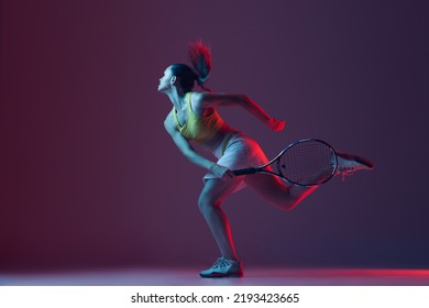 Full length portrait of young woman playing tennis isolated on dark background in neon. Healthy lifestyle. The practicing, fitness, sport, exercise concept. The female model in motion or movement - Powered by Shutterstock