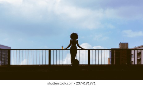 Full length portrait of a young woman standing in concrete bridge. Urban scene of girl in contemplation. cup of juice in railings. Copy space and sky. - Powered by Shutterstock