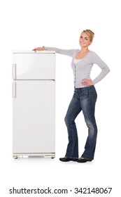 Full length portrait of young woman leaning on refrigerator over white background