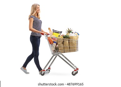 Full length portrait of a young woman pushing a shopping cart full of groceries isolated on white background