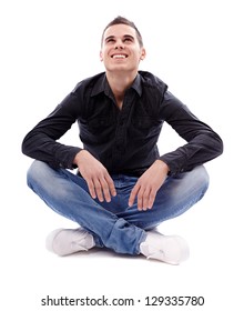 Full Length Pose Of Young Man Sitting On The Floor Cross Legged, Isolated On White Background