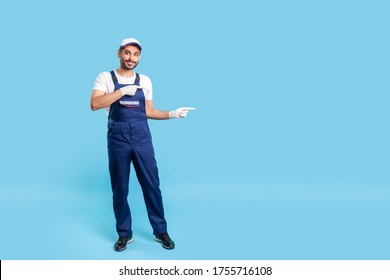 Full length positive handyman in uniform pointing at copy space, advertising area for idea presentation. Profession of service industry, builder or contractor. studio shot isolated on blue background - Powered by Shutterstock