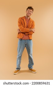 full length of positive young man with red hair standing with crossed arms on beige - Shutterstock ID 2200859631