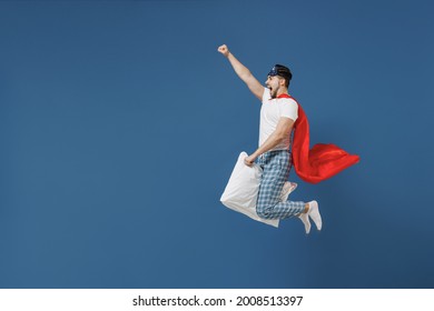 Full Length Powerful Young Man In Pajamas Jam Sleep Mask Superhero Suit Rest Home Jump High Fly On Pillow Have Supernatural Abilities Isolated On Dark Blue Background Good Mood Night Bedtime Concept.