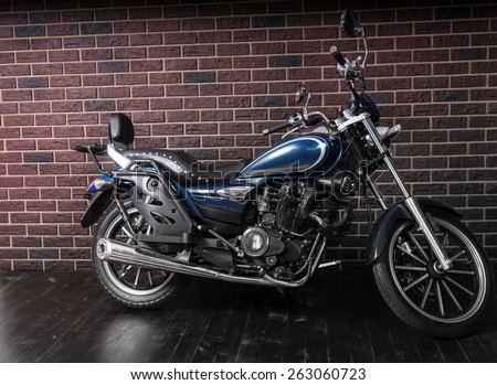 Full Length Profile of Blue Standard Cruiser Style Motorcycle in front of Brick Wall