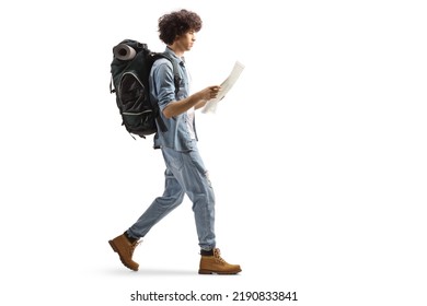 Full length profile of a male traveler with a backpack walking and reading a map isolated on white background - Powered by Shutterstock