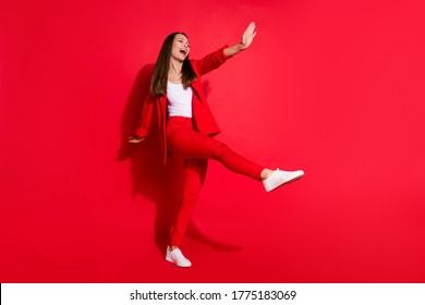Full length profile photo of attractive funny business lady success worker walk home street vacation having fun wear office blazer suit pants white shoes isolated bright red color background