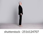 Full length profile photo of charming successful retired lady wear black suit isolated on grey color background