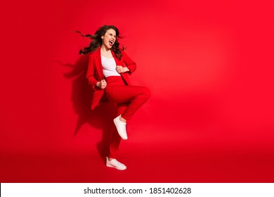 Full Length Profile Photo Of Charming Young Girl Crazy Open Mouth Raise Knee Wear Blazer Pants Footwear Isolated Red Color Background