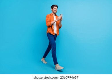 Full length profile photo of cheerful nice man hold use smart phone texting typing post isolated on blue color background - Powered by Shutterstock