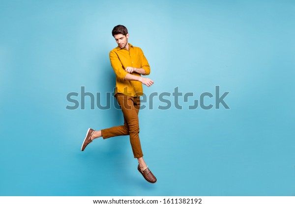 Full length profile photo of funny\
guy jumping high visiting shopping mall fixing clothes metrosexual\
wear yellow shirt pants isolated blue color\
background