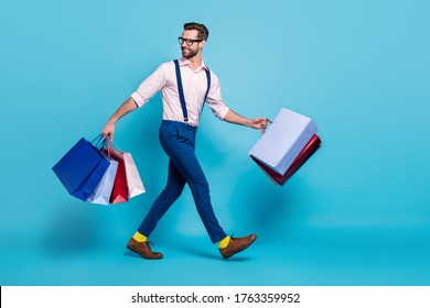 Full Length Profile Photo Of Handsome Business Man Carry Many Bags Buy Vacation Stuff Shopping Center Good Mood Wear Specs Shirt Suspenders Pants Boots Isolated Blue Color Background