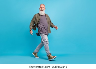 Full length profile photo of impressed old man go wearing khaki shirt jeans shoes isolated over blue color background - Powered by Shutterstock