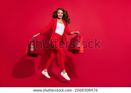 Full length profile photo of lovely brunette lady jump shopping wear suit shoes isolated on red color background