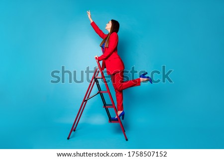 Full length profile photo of professional fancy lady worker come up career ladder touch success with arm wear luxury red suit blazer pants high-heels isolated blue color background