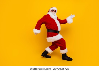 Full length profile portrait of positive santa walking empty space new year offer isolated on yellow color background - Powered by Shutterstock