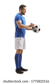 Full Length Profile Shot Of An Athlete Signing An Autograph On A Soccer Ball Isolated On White Background