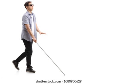 Full length profile shot of a blind young man with a cane walking isolated on white background