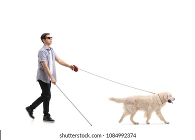 Full Length Profile Shot Of A Blind Young Man Walking With The Help Of A Dog Isolated On White Background