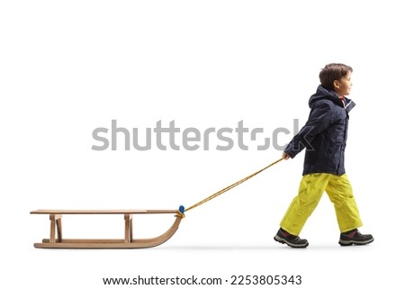 Full length profile shot of a boy pulling a wooden sleigh isolated on white background